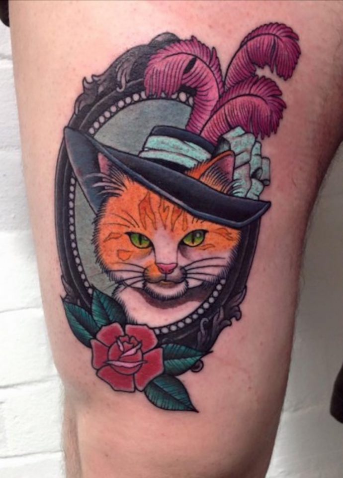 Un original tatuaje de un gato con sombrero, en colores vivos y con mucho detalle